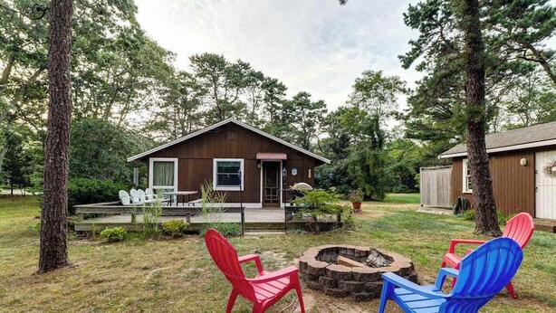 A cabin with a deck, outdoor seating, and a fire pit. - Comfy Cabin with Deck, Firepit, & Bike Path Access - Walk to Nauset Light Beach (Eastham)