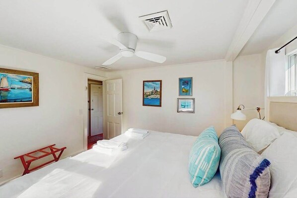 Une chambre d’hôtel avec un lit, un ventilateur de plafond, une porte et des œuvres d’art murales.