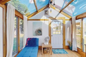 Habitació acollidora amb un finestral, un ventilador, un sofà i una porta.