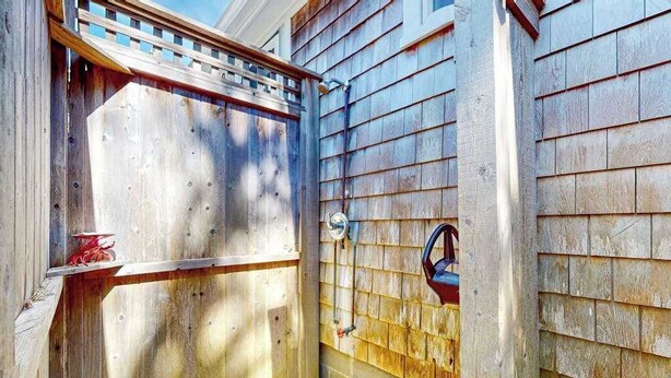 Een houten poort met een metalen handvat, een klein plankje met een rood voorwerp, en een ster-decoratie aan de muur.