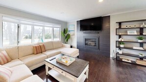 Ein Wohnzimmer mit Sofa, Couchtisch, Kamin, Fernseher und Regalen.