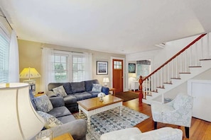 A living room with a sofa, coffee table, and patterned rug. - Bright spacious downtown home; walk to beach & lighthouse (Edgartown)