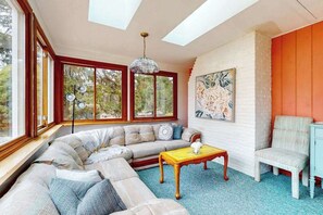 Ein Wohnzimmer mit Ecksofa, Couchtisch, Sessel und einem Gemälde an der Wand.