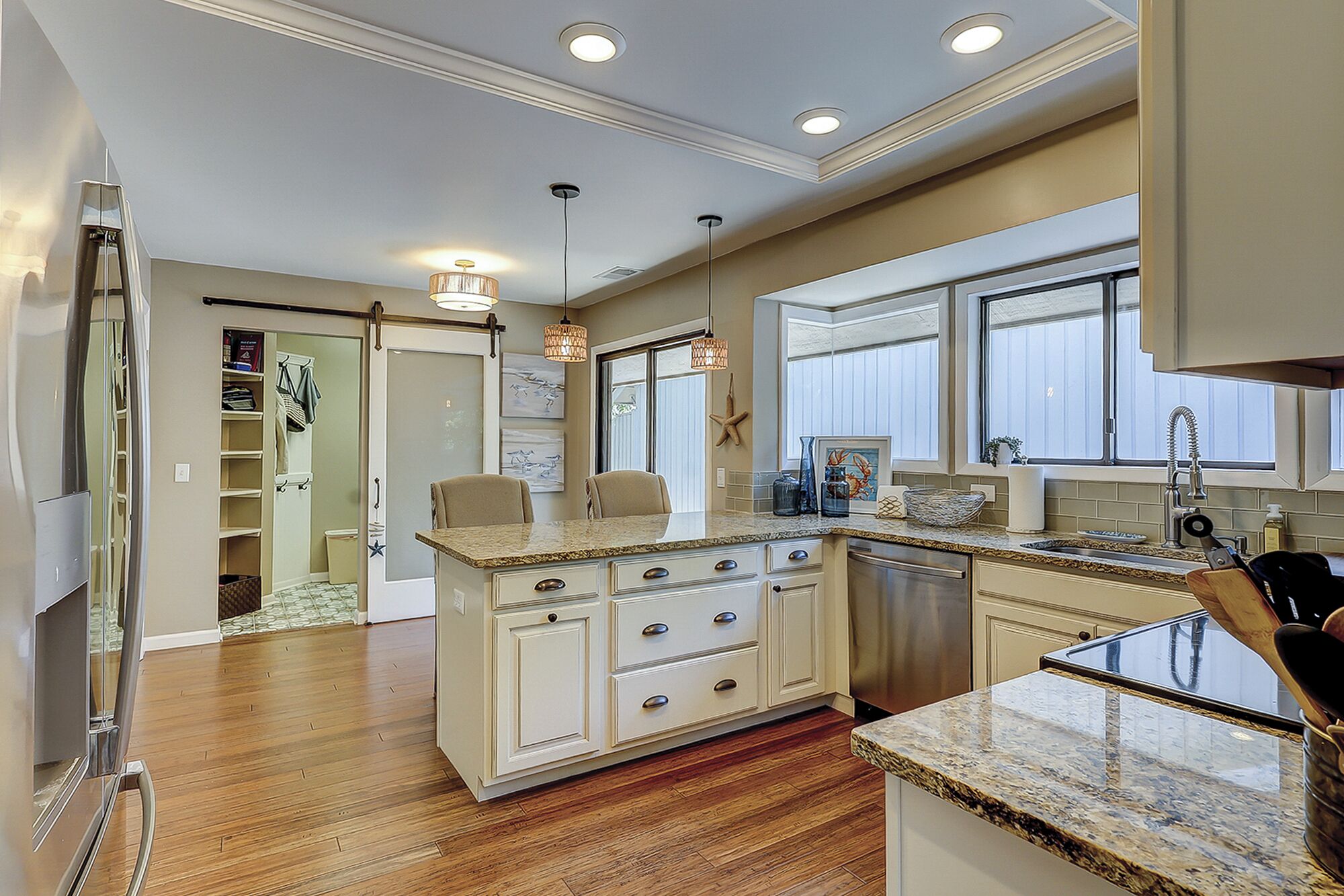 A kitchen with a central island, wooden flooring, and a view of the adjacent living area.