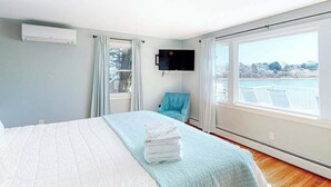 Ein Schlafzimmer mit einem Bett, einem Fernseher, einem Sessel und einem Fenster mit Blick.