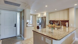 A kitchen with a granite countertop, stainless steel appliances, and beige cabinetry. - Sunset Rentals | Island Club 6205 (Hilton Head Island)