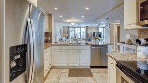 A modern kitchen with stainless steel appliances, white cabinetry, and a central island with a sink. - Sunset Rentals | Island Club 6205 (Hilton Head Island)