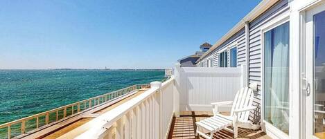 Ein Balkon mit Blick auf das Meer, mit weißen Geländern und zwei weißen Stühlen.