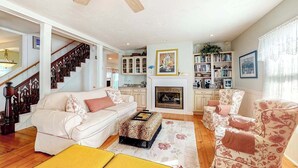 Una sala de estar con sofá, sillones, chimenea y escalera.