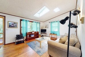 A living room with a sofa, coffee table, TV, bookshelf, and a ceiling light fixture.