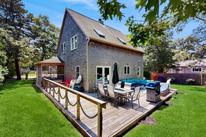 A two-story house with a deck, outdoor seating, and a swimming pool. - Newly remodeled home w/ new furniture, large yard & great porches (Oak Bluffs)