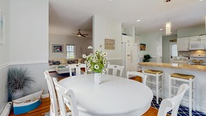 Una cucina moderna con mobili bianchi, un piano di lavoro in legno e un'area pranzo con tavolo e sedie bianche.