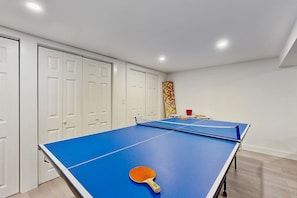 A room with a ping pong table, a single ping pong paddle, and a red bucket. - Newly remodeled home w/ new furniture, large yard & great porches (Oak Bluffs)