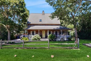 A two-story house with a front porch, a chimney, and a fenced yard. - Newly remodeled home w/ new furniture, large yard & great porches (Oak Bluffs)