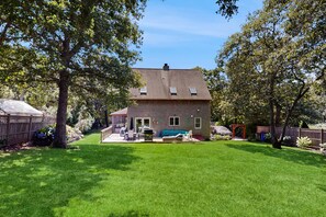 Ein zweistöckiges Haus mit überdachter Veranda, Rasen und Holzzaun.