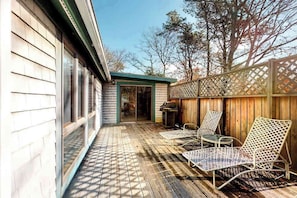 Une terrasse en bois avec des chaises et un barbecue.