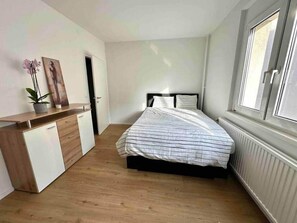 A bedroom with a bed, a dresser, a potted plant, and a window. - Budget Apartment in Vienna – Bright & Quiet (Vienna)