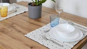 A dining table with a potted orchid, a glass of water, and a plate set for a meal. - Cozy Studio in Vienna – Great Value Stay (Vienna)