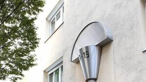 A building with a modern architectural design, featuring a large metallic structure near the entrance, a glass door, and a visible sign. - Cozy Studio in Vienna – Great Value Stay (Vienna)