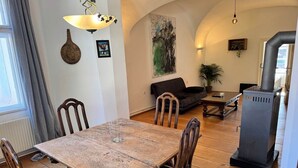 Zona pranzo con tavolo e sedie in legno, un divano, un quadro e un camino a legna.