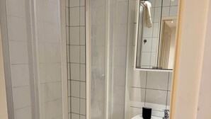 Un bagno con doccia vetrata, lavandino bianco e specchio.