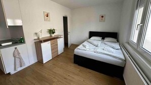 Une pièce de taille modeste comprenant un lit, une kitchenette et une petite salle de bain.