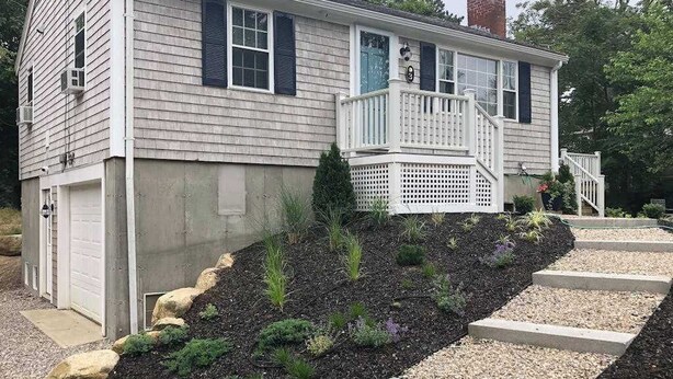 A two-story house with a front porch, a garage, and a landscaped front yard. - Peaceful perch near area's beaches with firepit, grill, streaming - dog-friendly (Harwich)