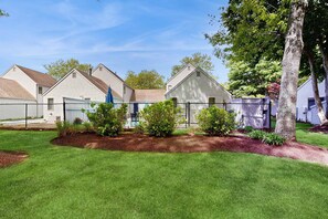 A row of white wooden cabins with a fenced yard and a tree. - Golf course-front townhouse with private heated pool & poolside patio (Mashpee)