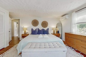 A bedroom with a large bed, two bedside tables, a dresser, and a window with a view. - Fantastic home near town & beach with fast WiFi, lawn games, play station & more (Hyannis)