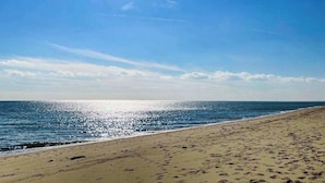 Una spiaggia con impronte che conducono all'acqua, un cielo sereno e l'oceano.