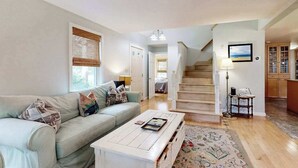 Un salon comprenant un canapé, une table basse et un escalier menant à une autre pièce.
