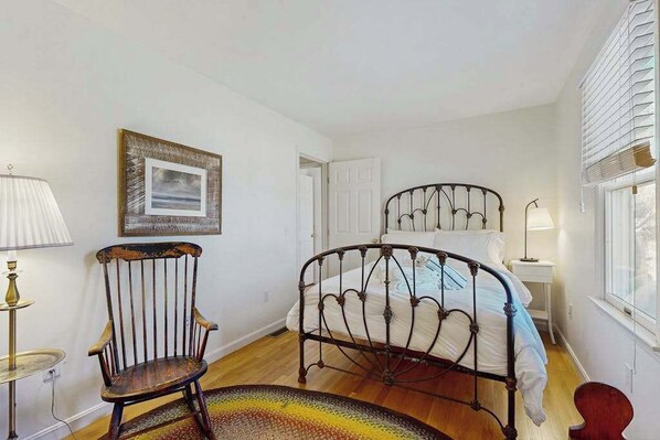 A bedroom with a double bed, a chair, a lamp, and a framed picture on the wall. - A well-appointed getaway near beach, Wifi, Gas grill, Fireplace (Chatham)