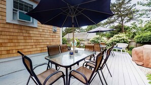 Une terrasse dotée d’une table et de chaises à plateau en verre, entourée de parasols.