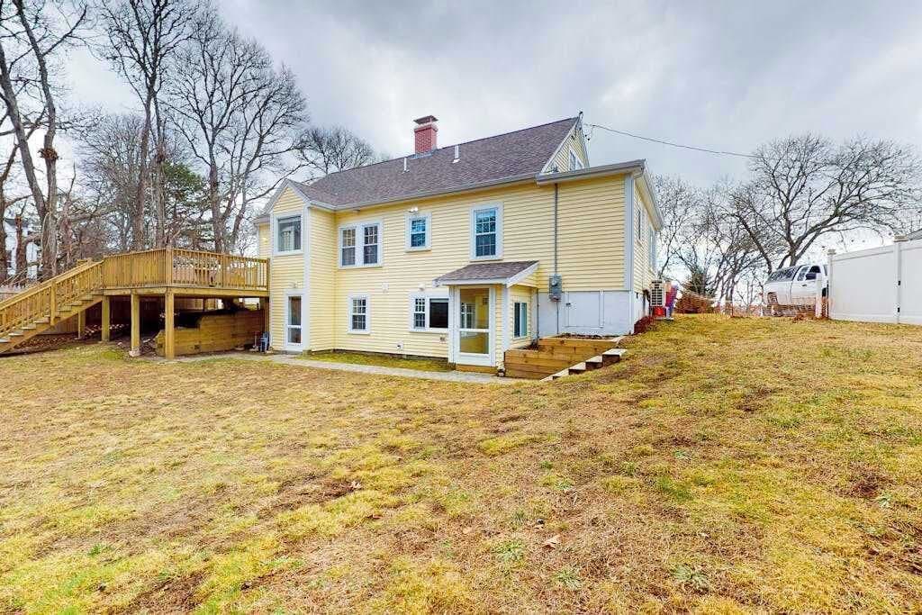 A two-story house with a front porch, a covered deck, and a small front yard.