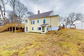 A two-story house with a front porch, a covered deck, and a small front yard.