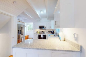 Una cocina moderna con armarios blancos, encimeras de granito y electrodomésticos de acero inoxidable.