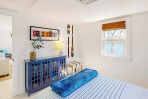 A bedroom with a bed, a blue cabinet, a window with a view, and a framed picture on the wall.