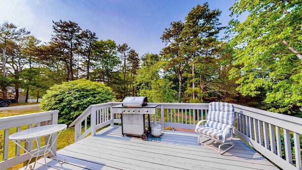 Une terrasse avec un barbecue, une table et une chaise.