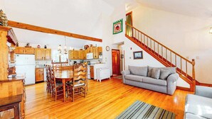 Un vaste espace de vie comprenant une table à manger en bois, un canapé et un escalier.