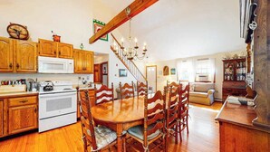 Une cuisine avec des meubles de rangement en bois, un four à micro-ondes, une cuisinière et une table à manger avec des chaises.