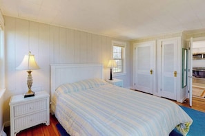 A bedroom with a bed, nightstands, a window, and a door. - Renovated cottage steps from private beach with backyard, grill, bay views, AC (Bourne)