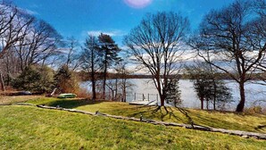 A lakeside view with a dock, grassy area, and trees. - Wonderful waterfront getaway with furnished deck, pond access, kayaks & WiFi (Cotuit)