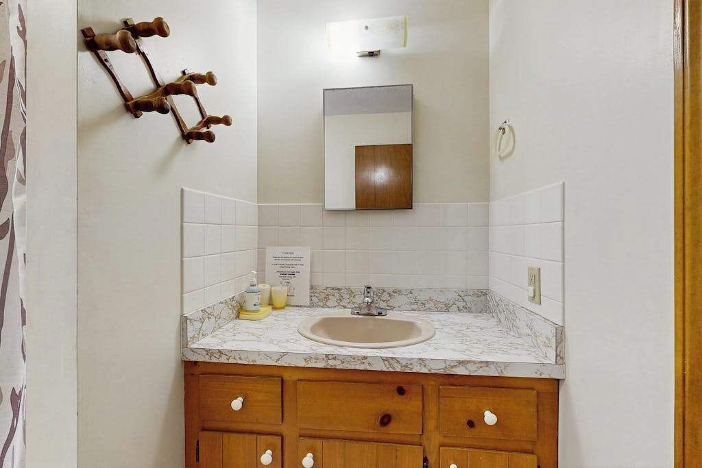 A bathroom with a marble sink, wooden cabinets, a mirror, and a towel ring.