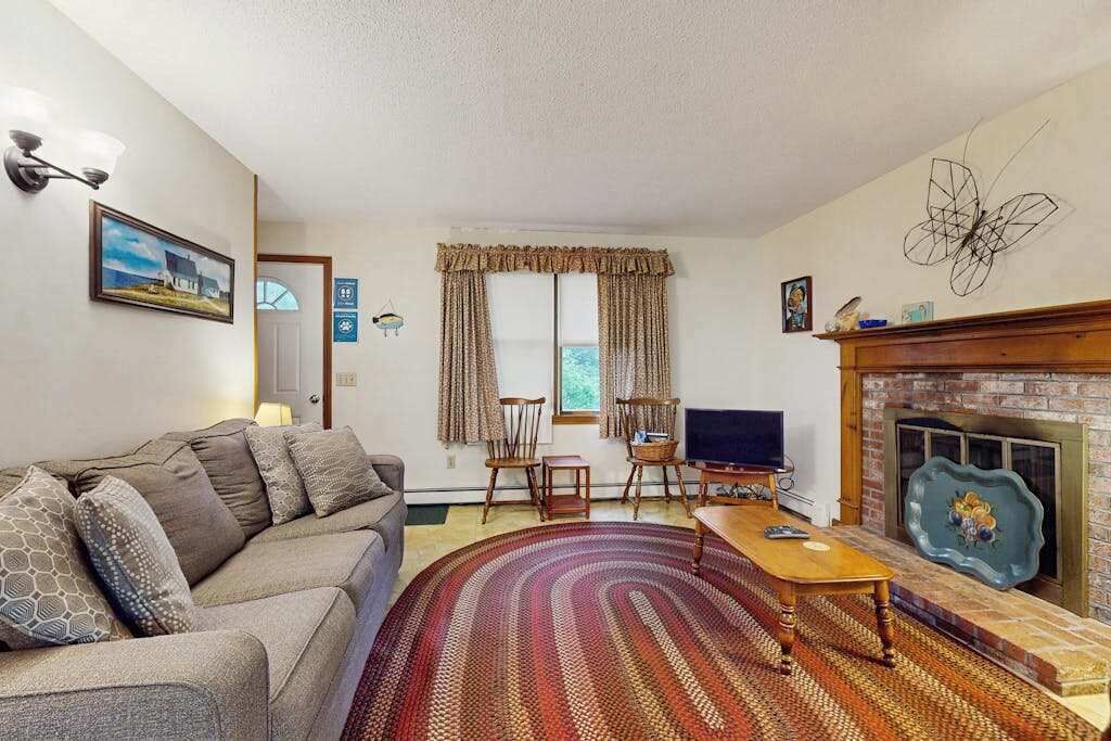A living room with a sofa, a television, a fireplace, and a window with curtains.
