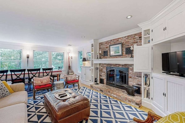 A living room with a fireplace, a television, and a patterned rug. - Cozy home on lake including local beach pass , hot tub, patio, W/D, & AC (Centerville)