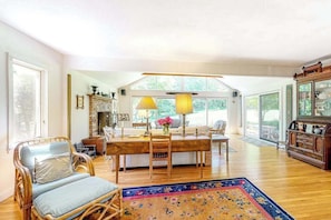 A spacious living room with a wooden dining table, chairs, and a large window. - Private Hillside Home, Fully Equipped Kitchen, Dog-Friendly, A/C, W/D (Chilmark)
