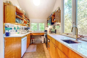 A kitchen with wooden cabinets, a sink, and a window with a view of trees. - Private Hillside Home, Fully Equipped Kitchen, Dog-Friendly, A/C, W/D (Chilmark)