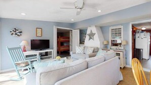A living room with a sofa, TV, and a ceiling fan. - Classic Cape Cod home with Patio and Firepit - Walk to the Beach (Dennis Port)