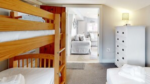 A bedroom with bunk beds, a white dresser, and a view into another room. - Classic Cape Cod home with Patio and Firepit - Walk to the Beach (Dennis Port)