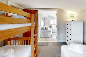 A bedroom with bunk beds, a white dresser, and a view into another room. - Classic Cape Cod home with Patio and Firepit - Walk to the Beach (Dennis Port)
